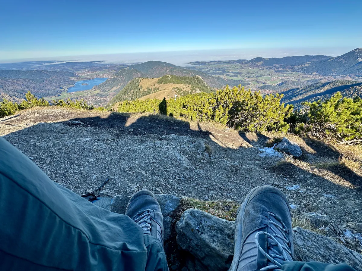 Blick vom Jägerkamp über den Spitzingsee, mit München in der Ferne unter dicken Wolken.