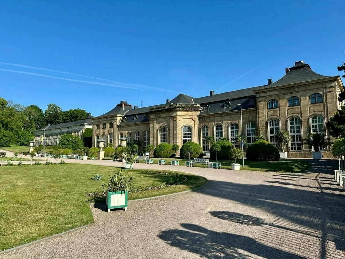 Die Orangerie in Gotha mit einem gepflegten Garten und klarem Himmel im Hintergrund.