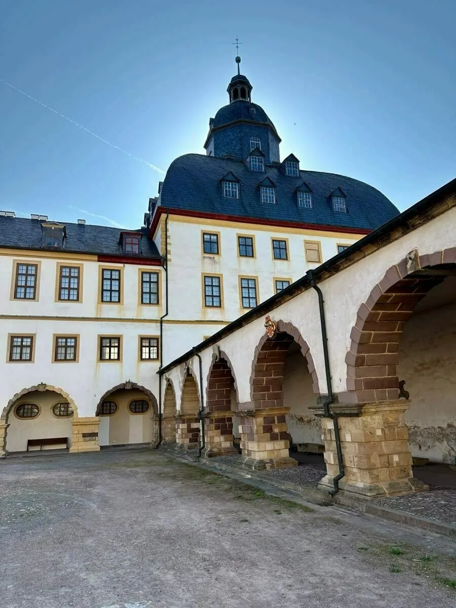 Der originale Turm vom Schloss Friedenstein und die umgebenden Arkaden unter einem klaren blauen Himmel.