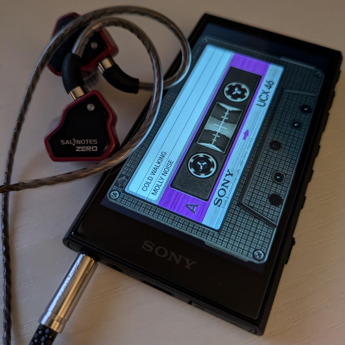 Froey's Walkman with a small pair of in ear monitors from 7hz. The song Cold Walking by Molly Noise is being played using the casette view.