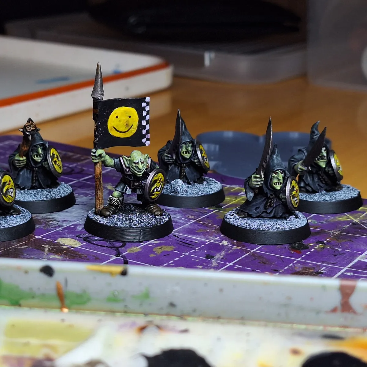 Goblin Miniatures. One is holding a banner with a bright yellow smiley face on it.