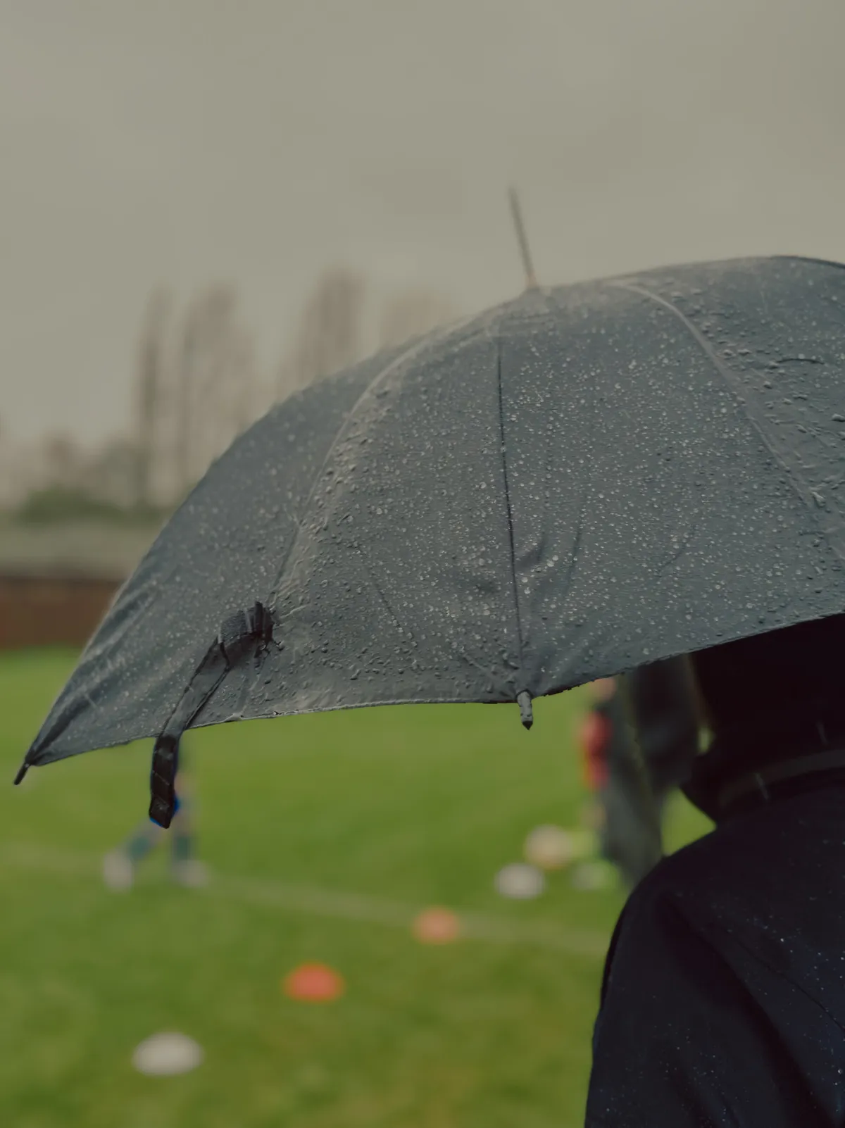 Looking at the soccer game with an umbrella