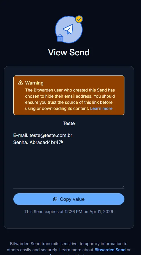 Captura de tela da interface "View Send" do Bitwarden em modo escuro. No topo, há um ícone azul de um avião de papel com um pequeno cadeado. Abaixo, um quadro de aviso laranja informa que o remetente optou por ocultar seu endereço de e-mail. O conteúdo compartilhado exibe o título "Teste", seguido pelo e-mail "teste@teste.com.br" e a senha "Abracad4br4@". Na parte inferior, há um botão azul com a inscrição "Copy value" e uma nota informando que o link expira em 11 de abril de 2026, às 12:26 PM.