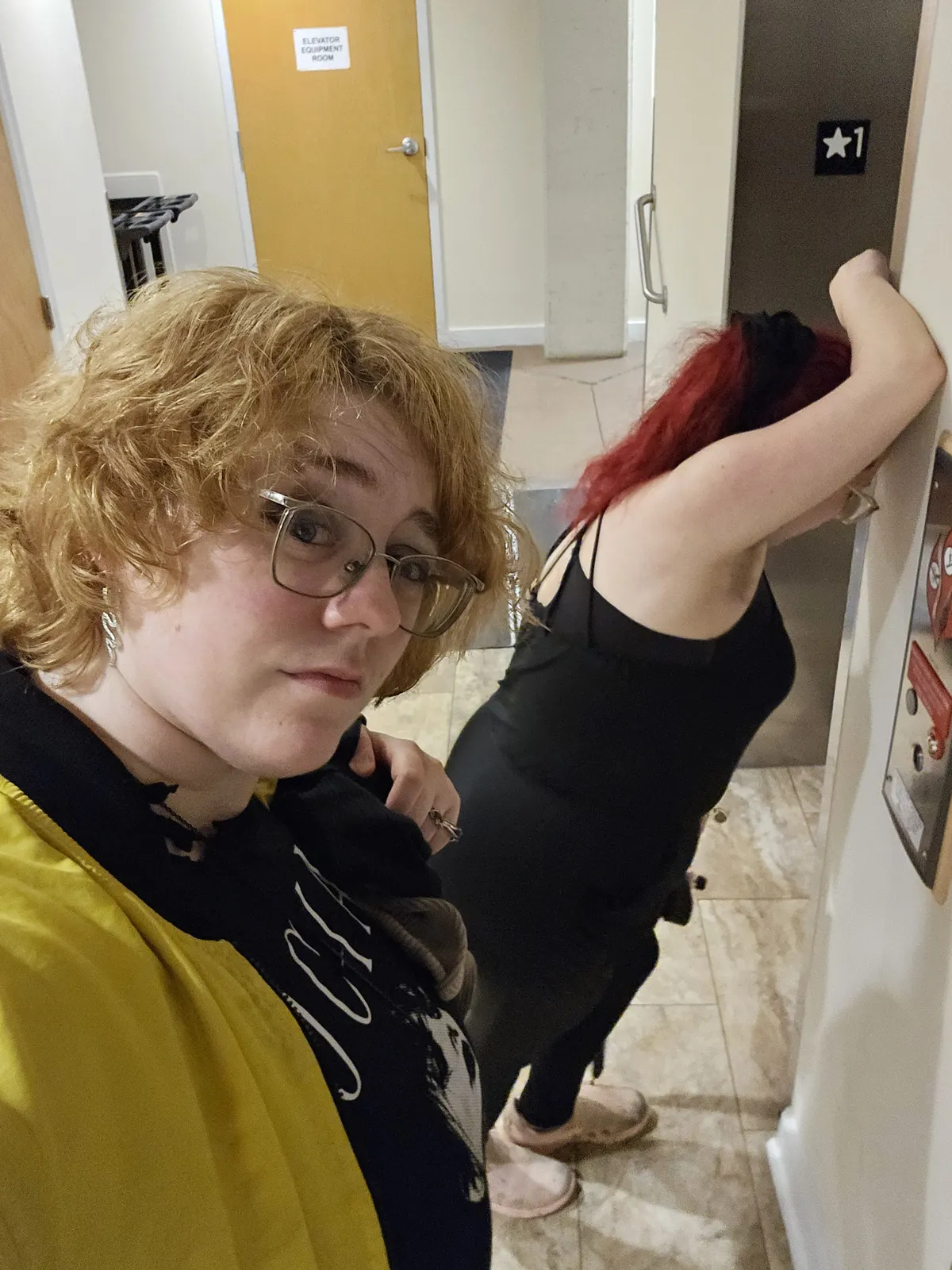 A selfie of myself and my wife waiting at the elevator. I'm doing the stupid Dreamworks eyebrow raise, while my wife is hunched over the button panel. We've had a lot to drink and God is punishing us for it.