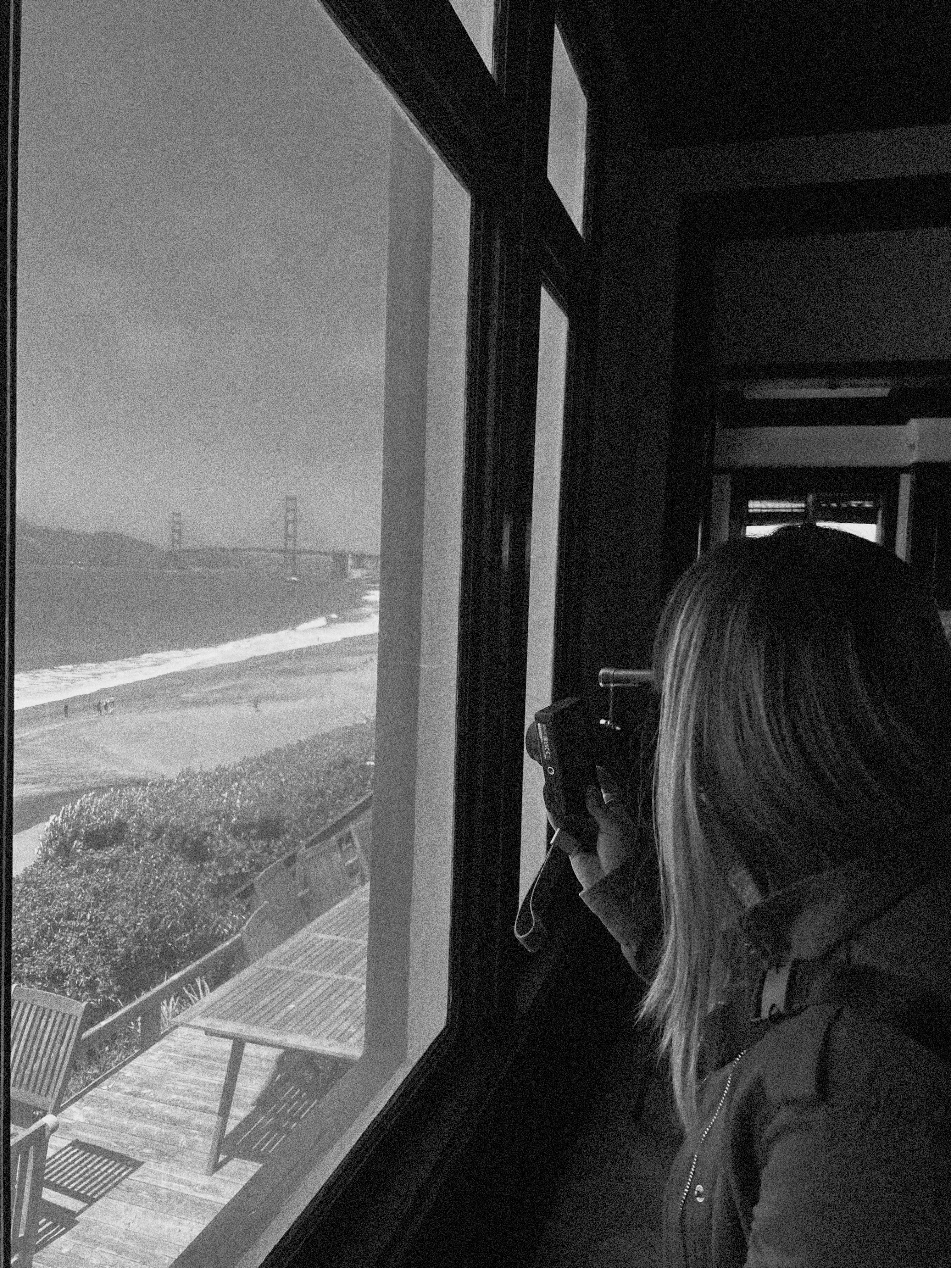 Girl with a camera taking a photo through a window