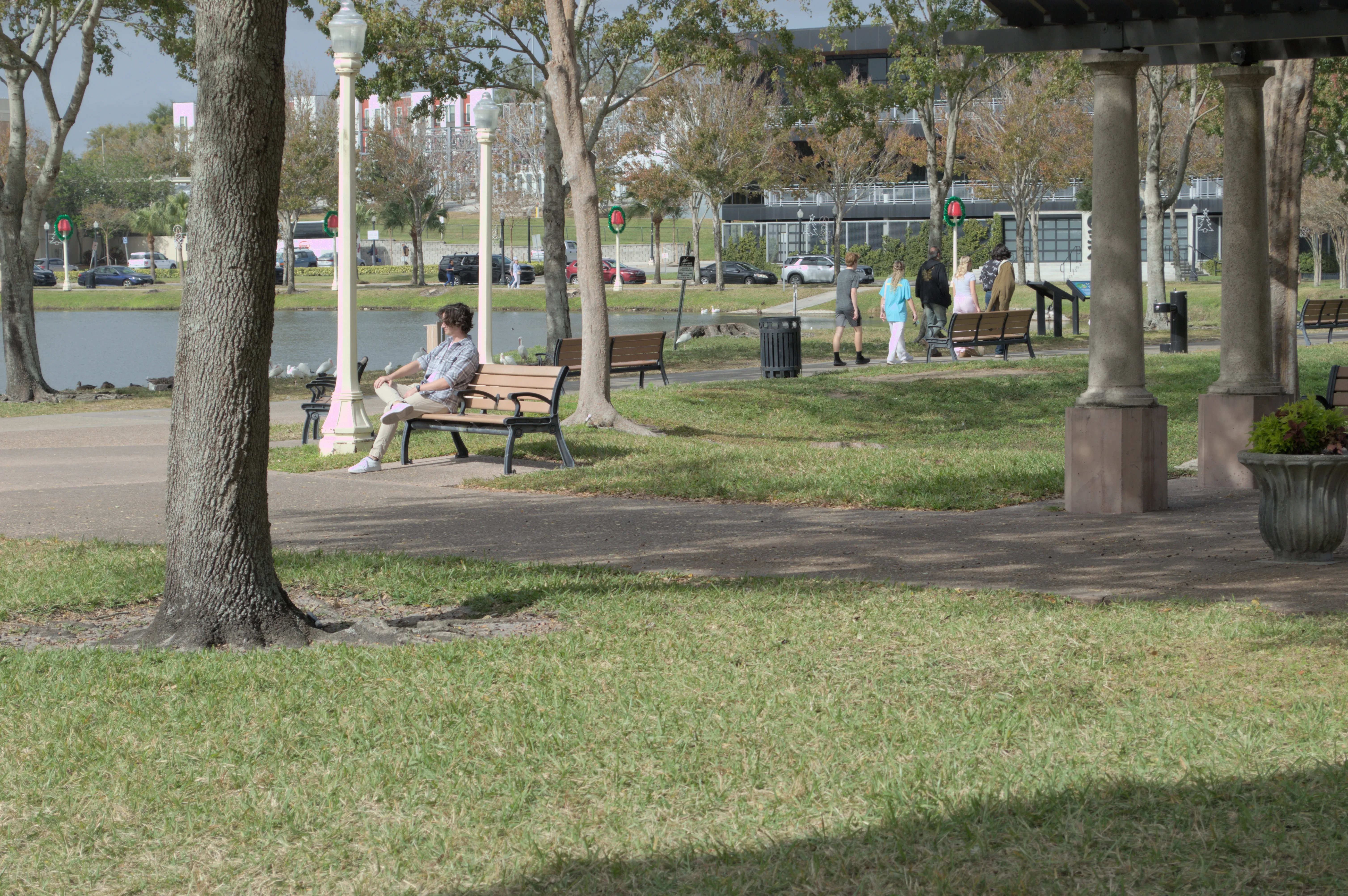 Josh sitting on a bench, waiting for Amaya to walk up with her mom. He's trying to act natural, inconspicuous.