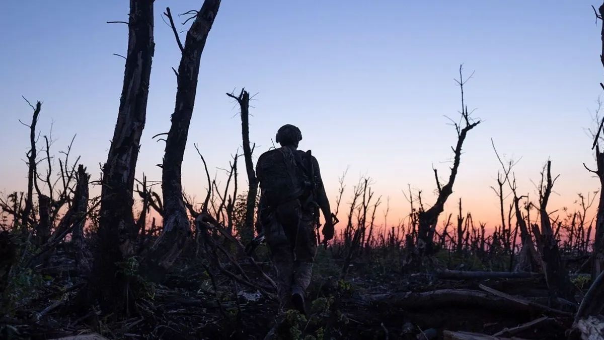 A Ukrainian soldier walking through a bombed out forest
