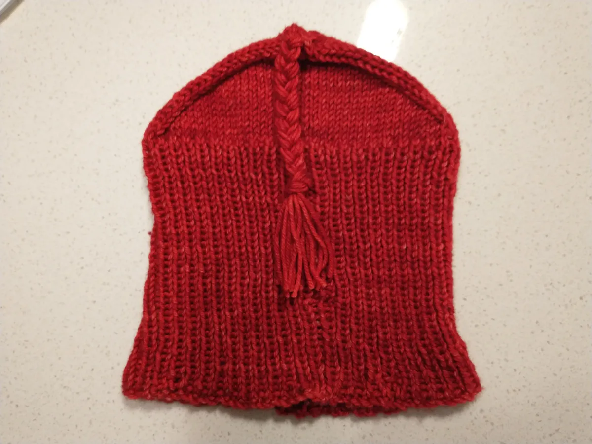 Red hand-knit hat with triangular crown and braided tassel