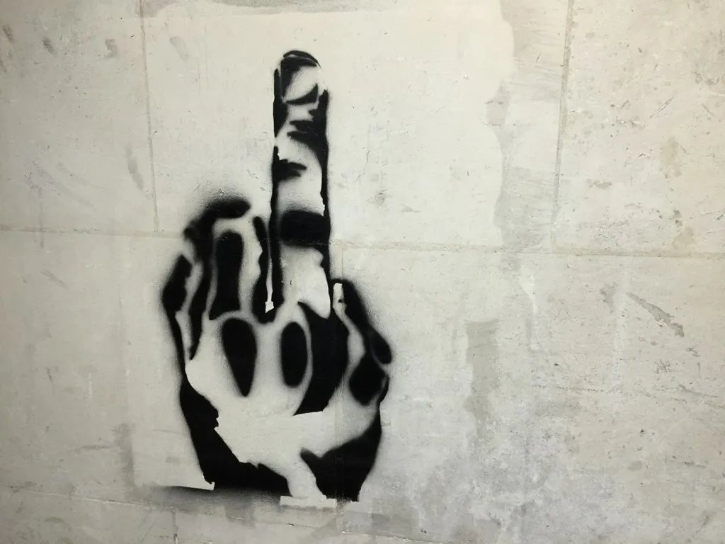 Stencil art of middle finger on stone wall