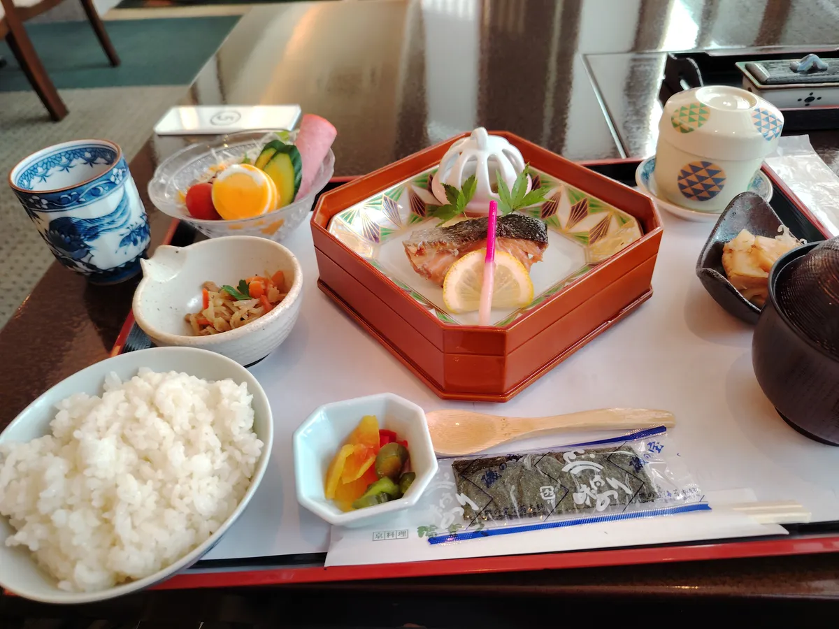 a traditional japanese breakfas consisting of fish, rice, miso soup, tea, pickled radish, an eggroll and some other stuff i don't know the name of.