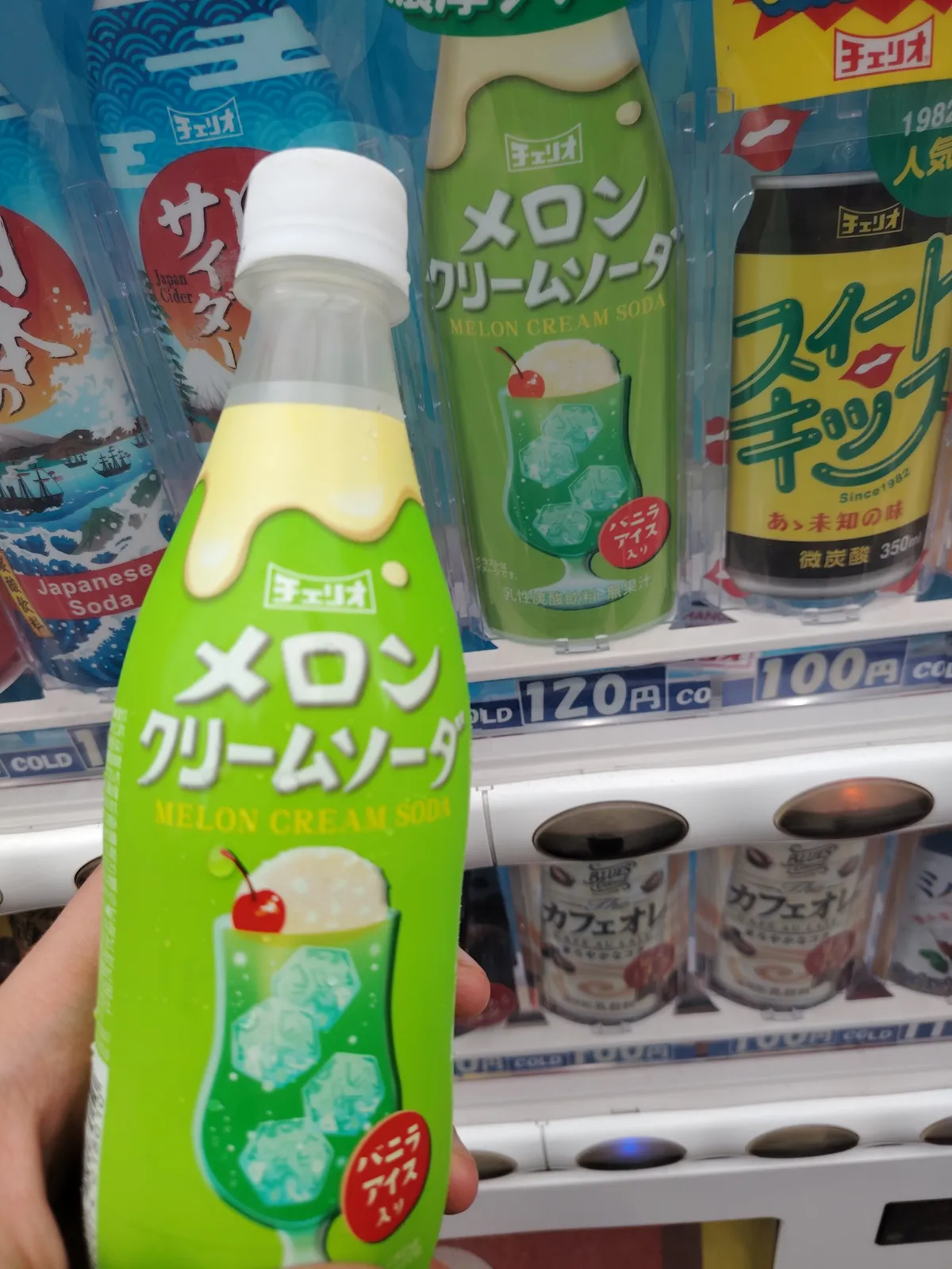 a green bottle filled with melon cream soda. The picture is taken in front of a vending machine.