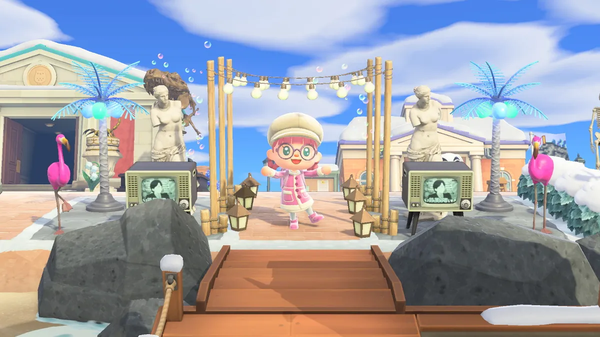Slothra is standing in the entrance of her island from the airport. There are lights stranded across poles, retro televisions, plastic flamingoes, large blue palm tree lights, and Venus de Milo statues