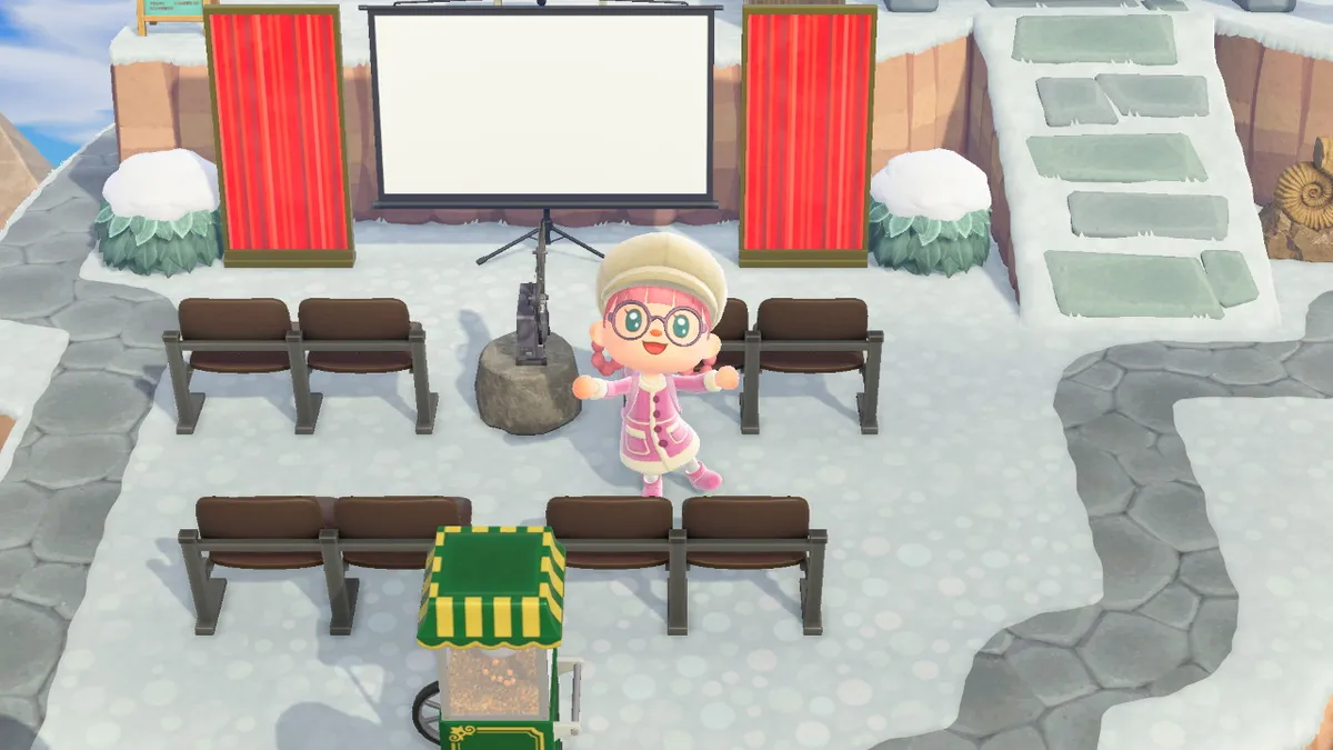 Slothra is standing in the middle of her outdoor cinema, with the screen behind her and the projector next to her. There's also plenty of seating and a popcorn machine.
