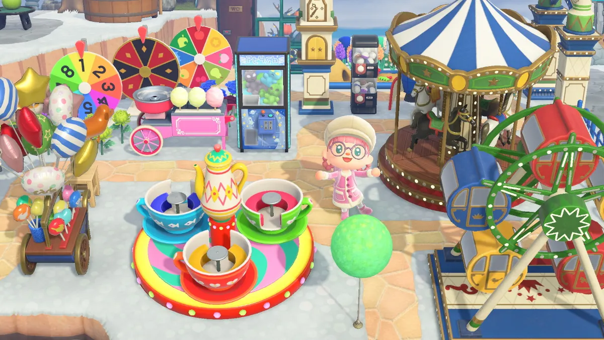 Slothra stands in the middle of the theme park, with a ferris wheel, a tea cups ride, a carousel, a balloon stall, a cotton candy maker, spinning wheels, crane machines, and gachapon machines