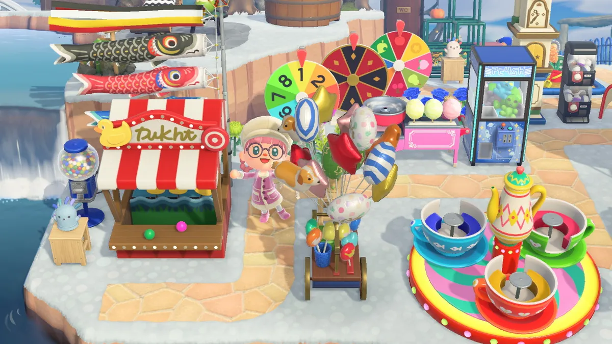 Slothra stands slightly to the left of the previous picture with the tea cups ride, the crane machine, the cotton candy maker, the spinning wheels, the balloon stall, a shooting gallery, and a gumball machine