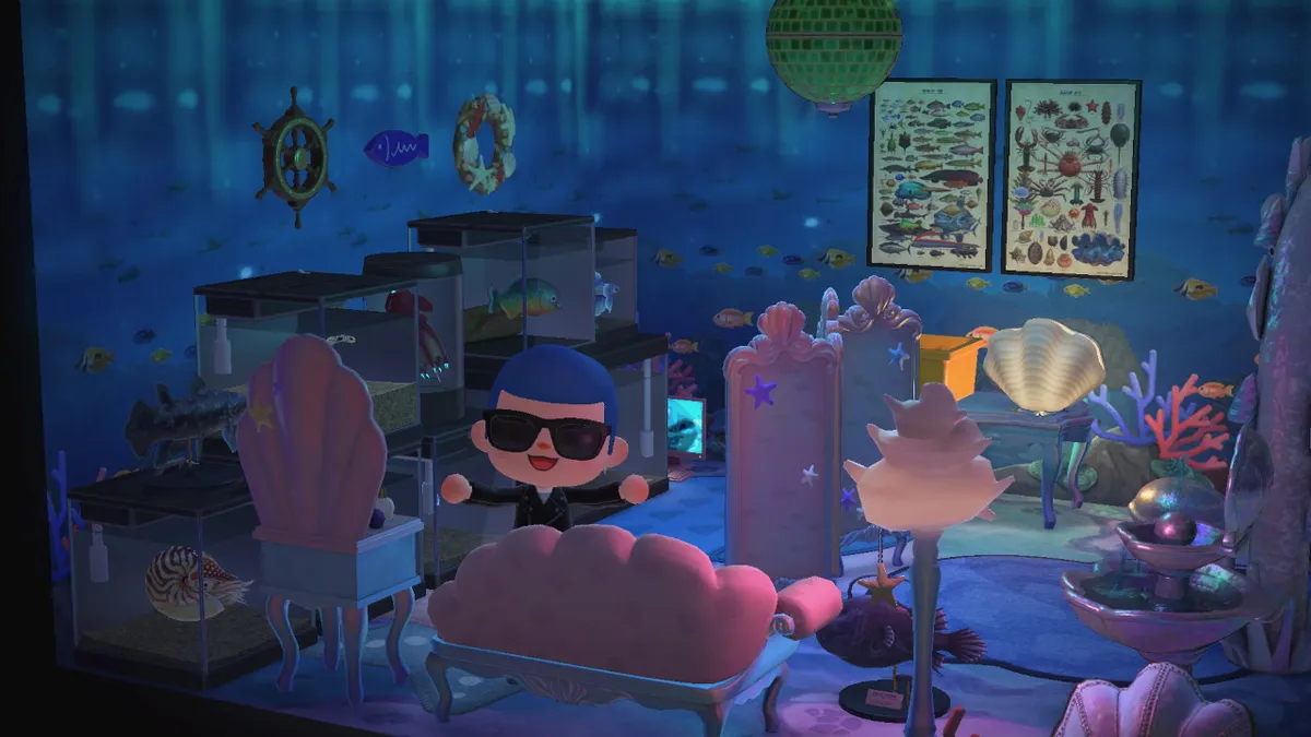 Slothra is standing in a room with under-the-sea wallpaper and dim lighting. There are several fish tanks to the left, fish posters on the wall, and mermaid furniture to the right.