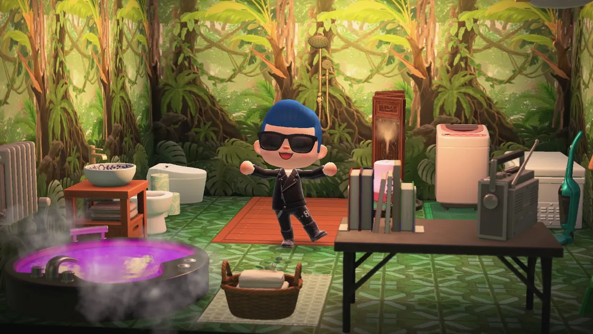 Slothra is standing in a bathroom with jungle wallpaper, green floor tiles, a shower, a toilet, a bidet, a sink, a large steaming tub, a table with books and a radio, and, in the back, a washing machine and a freezer.