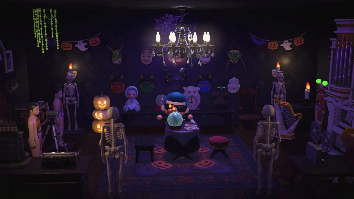 Slothra is hidden behind a crystal ball and candles on a table. There is a large chandelier above them. There are jack-o-lanterns, skeletons, anatomical figures, a pipe organ, scary dolls, scary masks, and other scary things.
