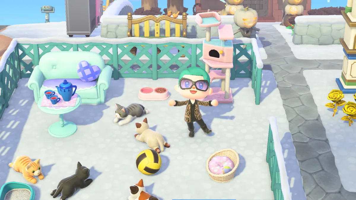 Slothra is standing in the middle of a fenced-off area that has a comfy couch, a tea seat on a table, and five cat plushes lying on the ground. The cats also have a litter tray, a bed, a food dish, and a cat tower.
