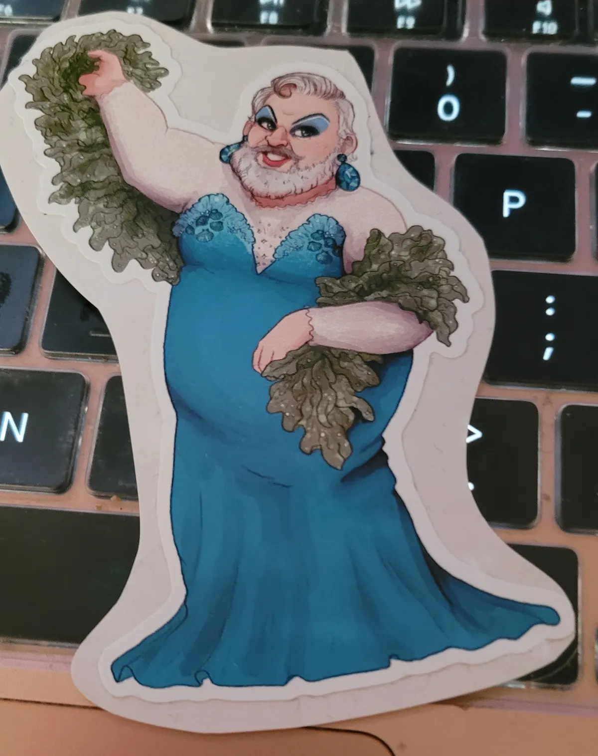 An illustration of the large beautiful bear of a man John Feeney from Our Flag Means Death, dressed in a stunning blue gown, with dramatic eye makeup, and carrying a boa made of seaweed, in his dragsona as Calypso, the Sea Goddess.