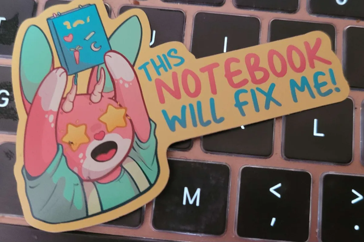 A cartoon jackelope, with stars for eyes, is holding up a notebook. Next to them is the phrase This Notebook Will Fix Me!