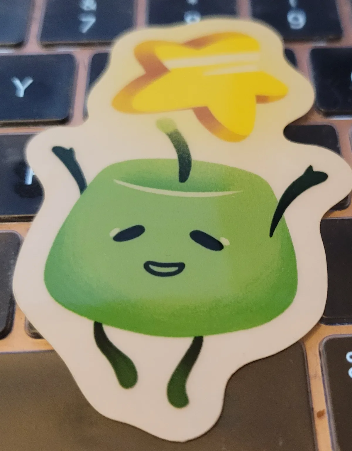 A green Junimo is standing up with its arms outstretched and a star above them.