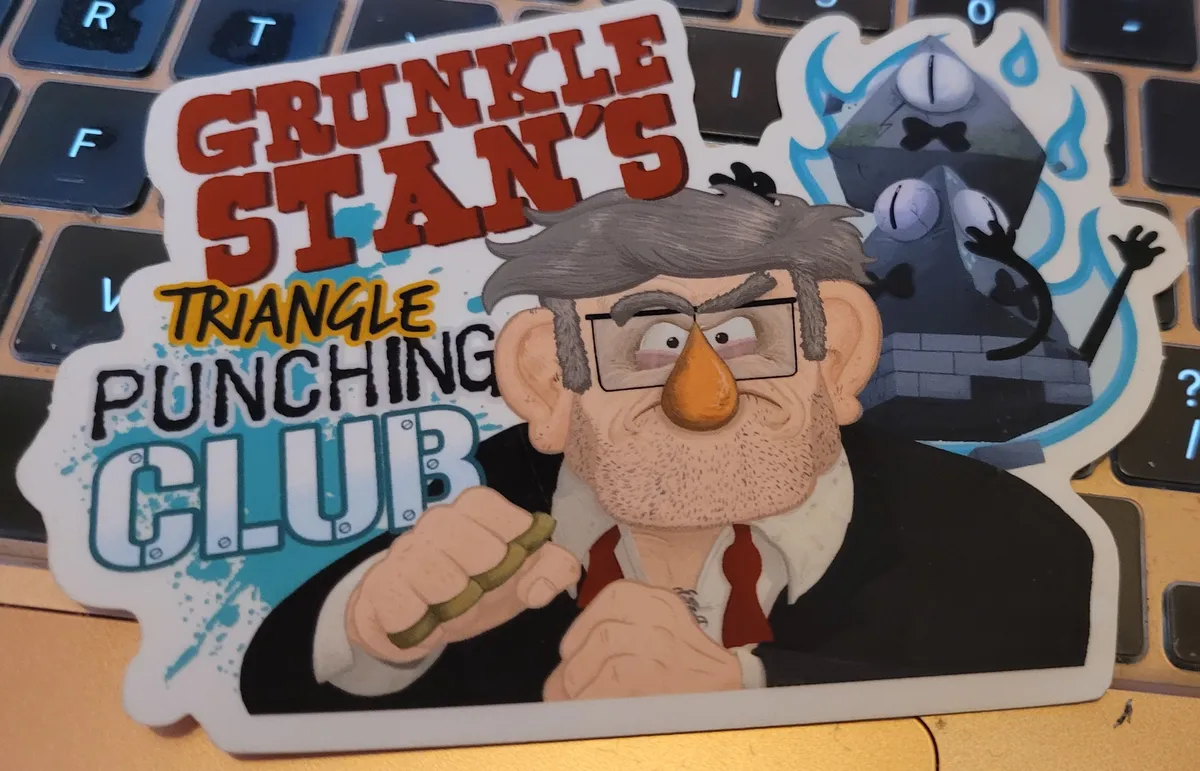 A sticker that says Grunkle Stan's Triangle Punching Club on the left, and has an illustration of Grunkle Stan on the right, ready to punch. Behind him are two sad looking pyramids that might be Bill Cipher.