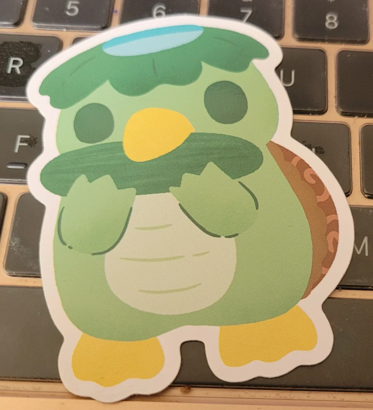 A cartoon kappa is biting on a cucumber lengthways.