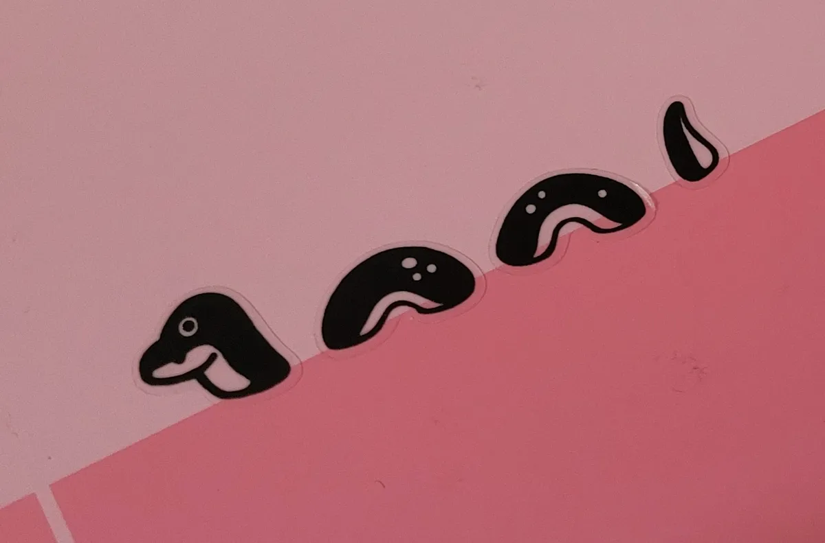 A collection of Loch Ness Monster stickers looking like it's swimming against the colour barrier on a notebook