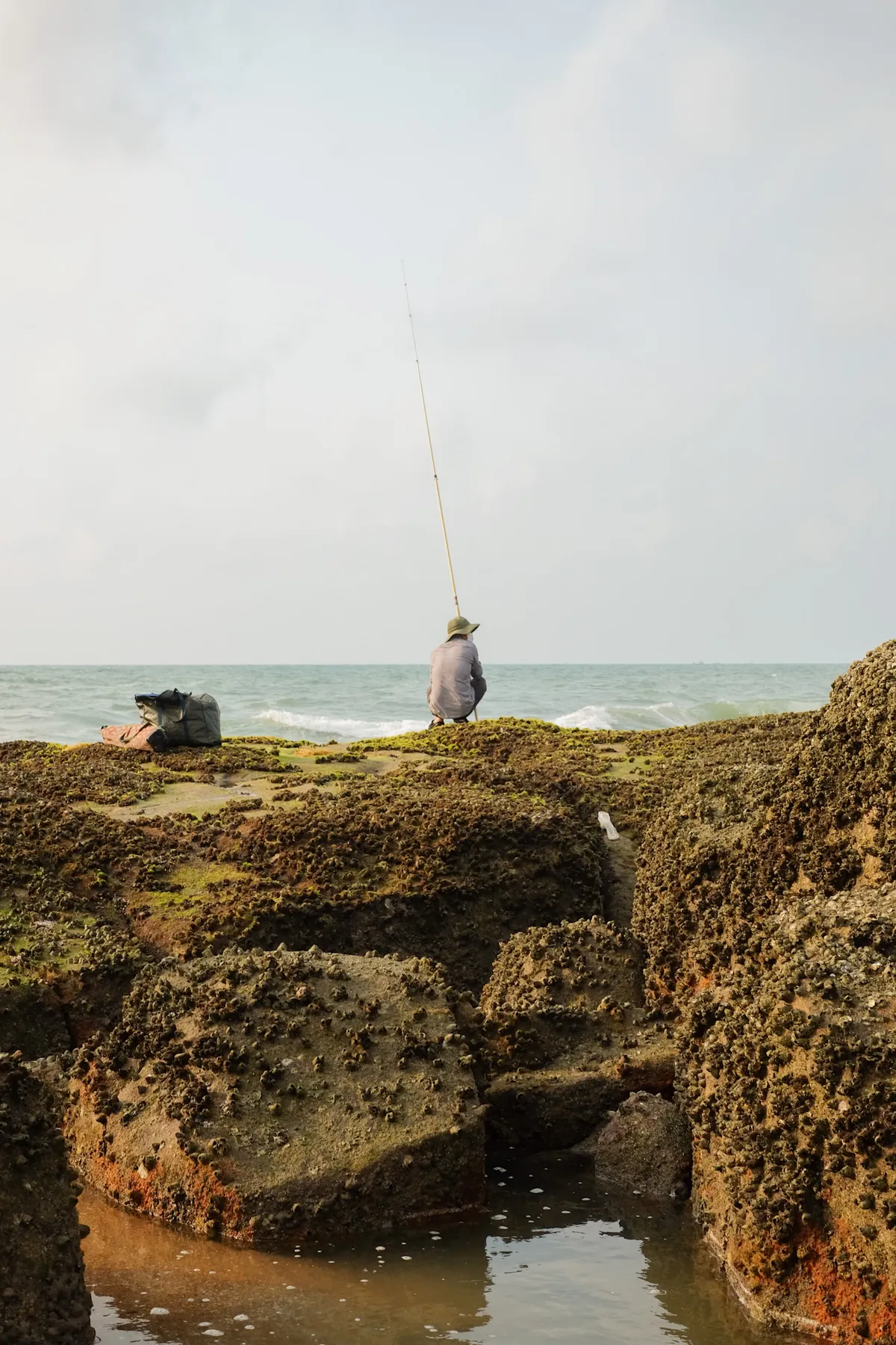A fisherman waiting for fish on sharp rocks