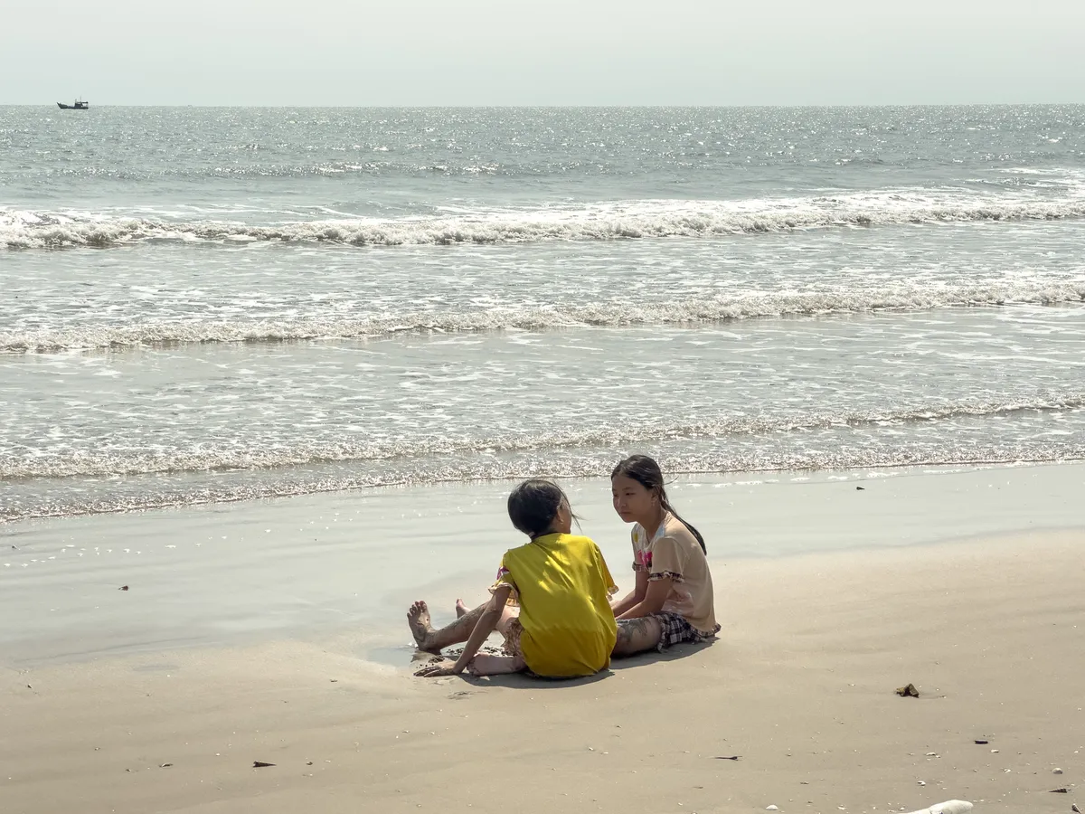 Two girls playing, talking by the coastline