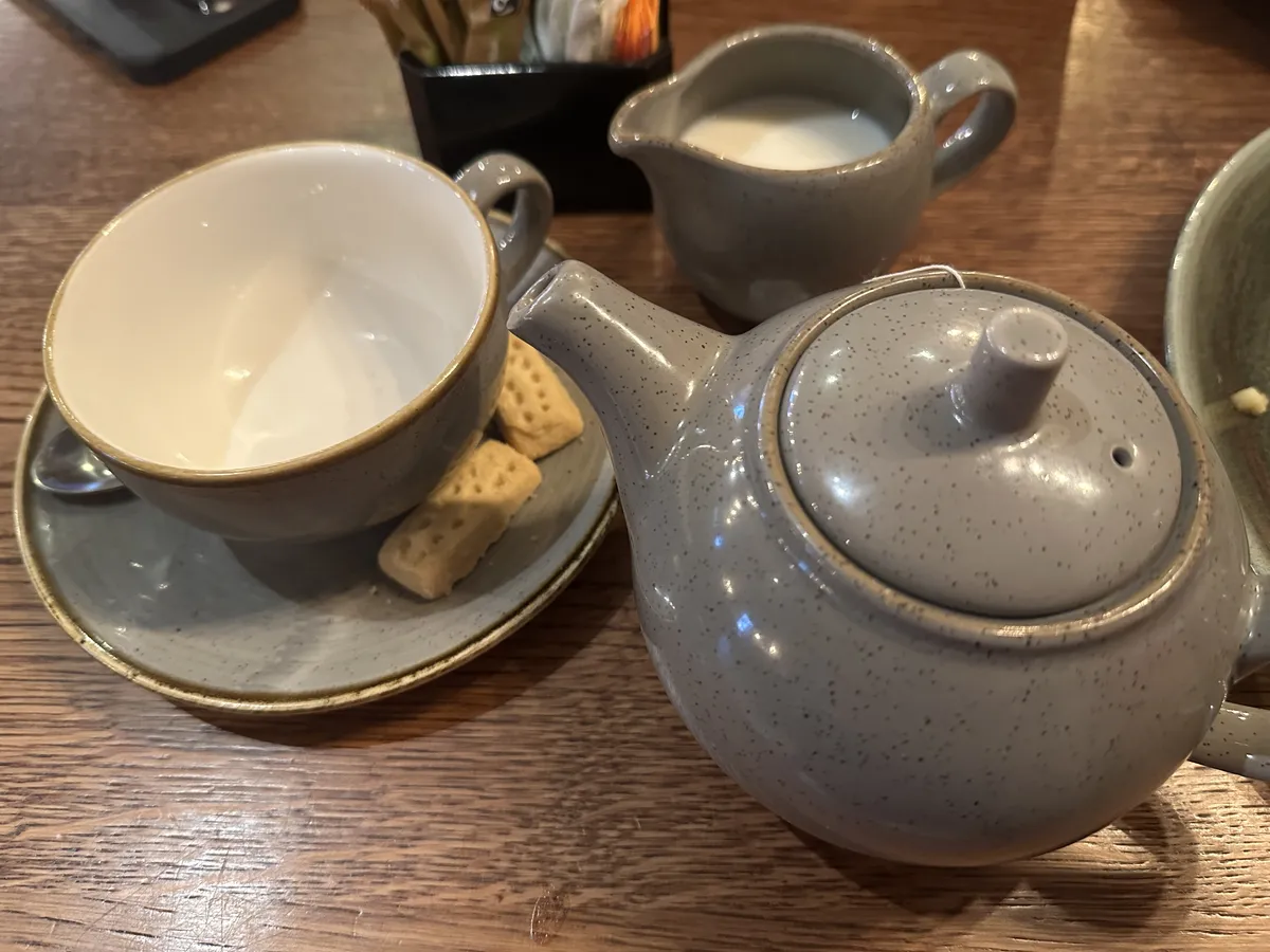 A tea set with milk, sugar, a teapot, a fancy cup and saucer