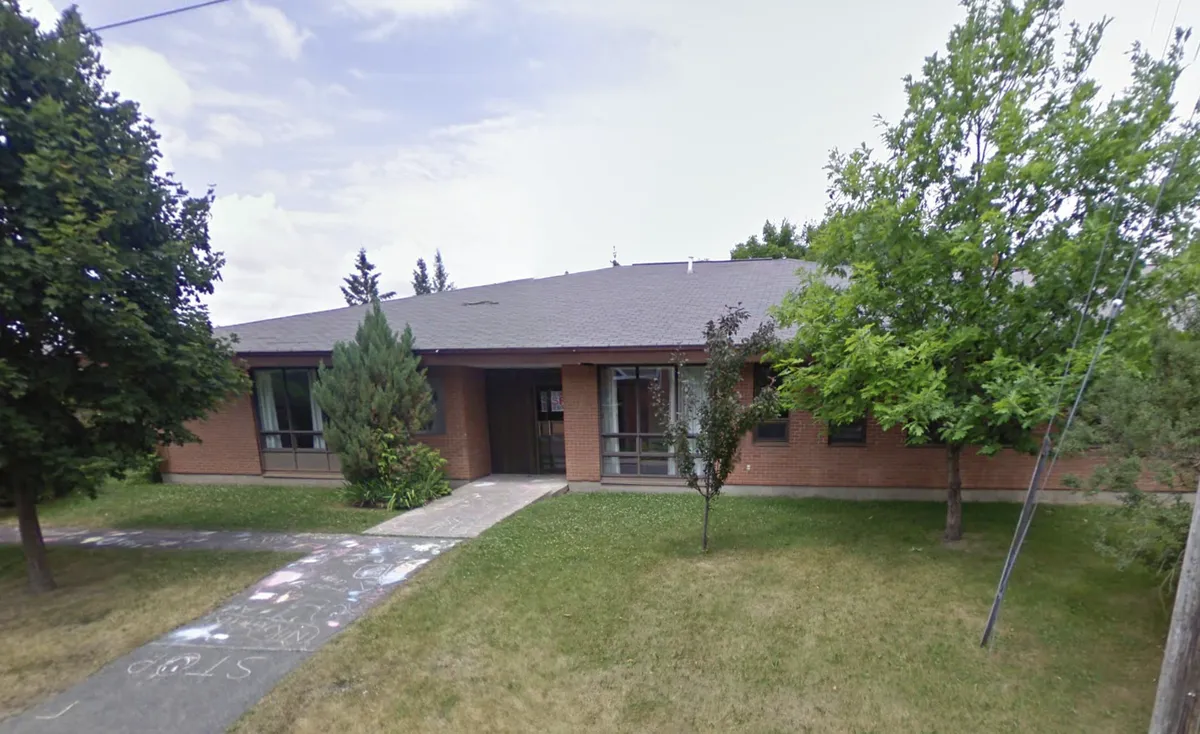 Photo of the side of a library and a patch of grass next to a tree