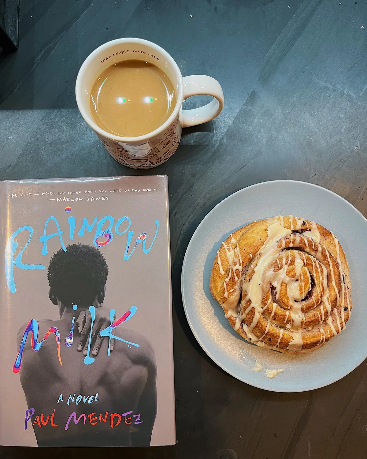 a book, cinnamon roll, and cup of coffee