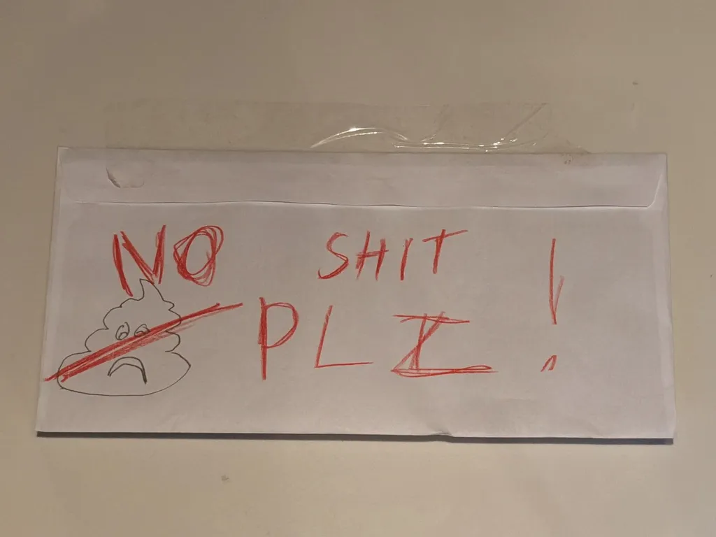Childlike warning sign taped above a broken toilet, reading โNO SHIT PLZ!โ with a crossed-out poop drawing. ๐