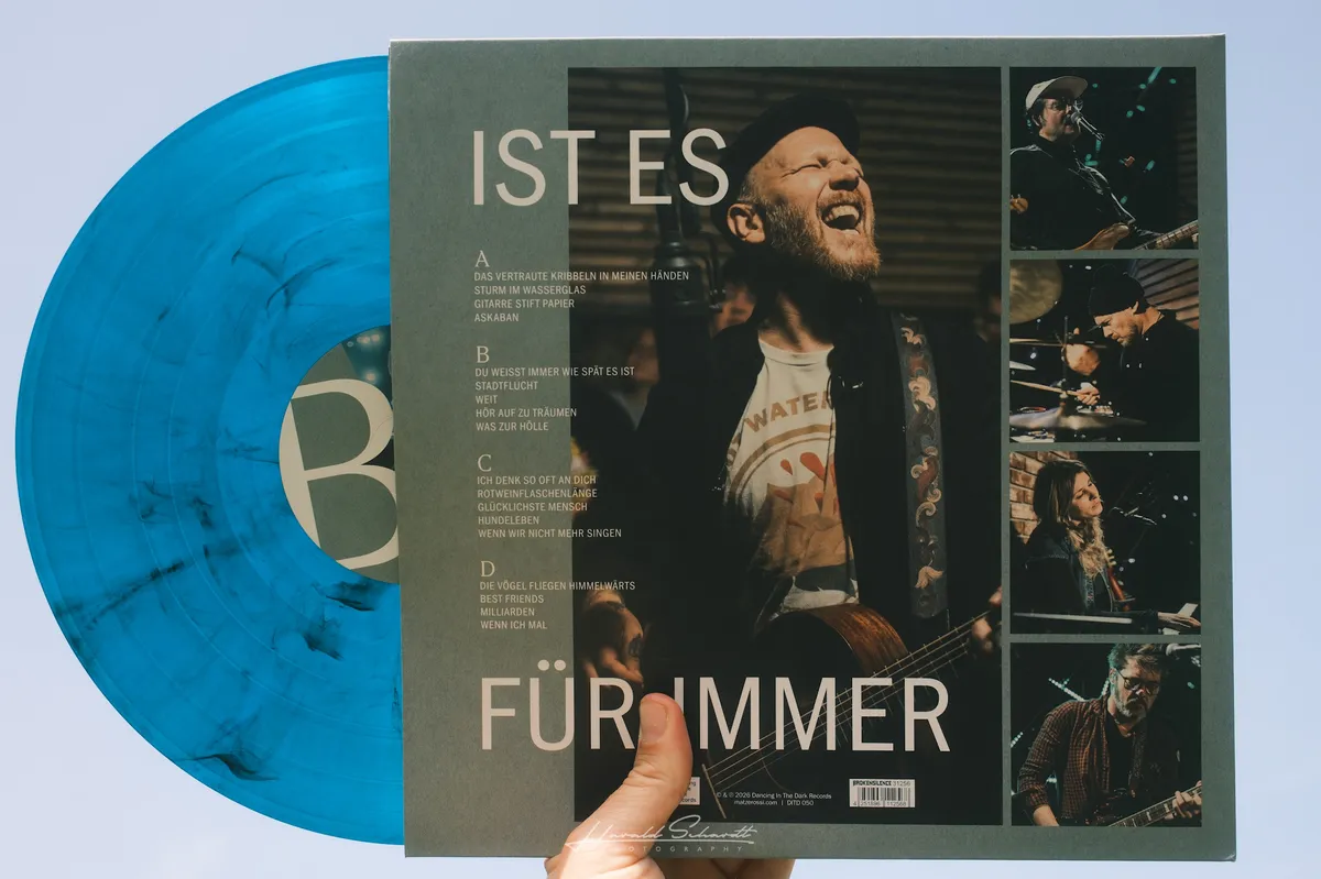 Matze Rossi — I Solange wir singen, ist es für immer. blue marble vinyl half out of the sleeve, held against a blue sky.