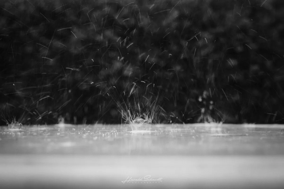 Raindrops splashing across a flat surface during a rain shower.