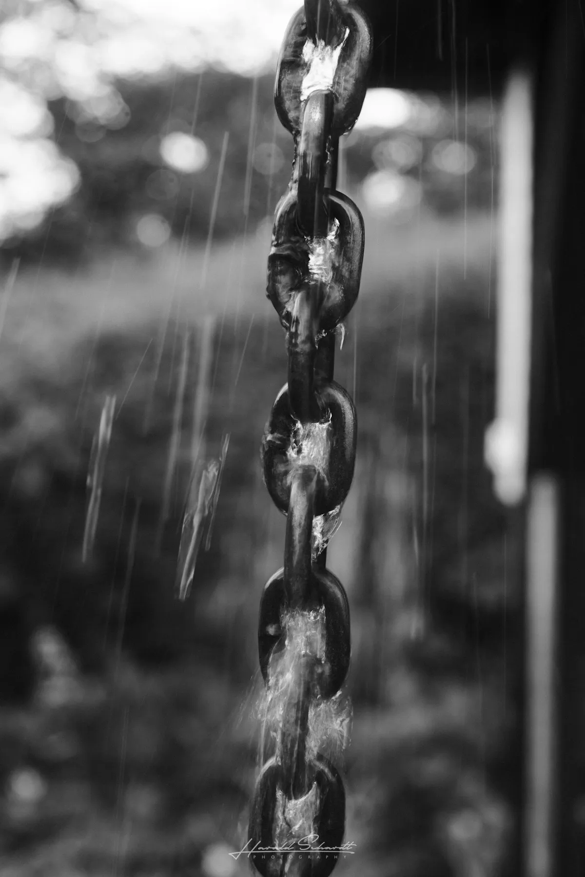 Rainwater running down a metal chain in heavy rain.
