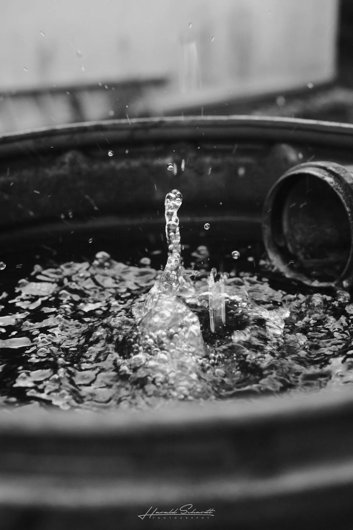 Raindrops splashing into a water-filled barrel.