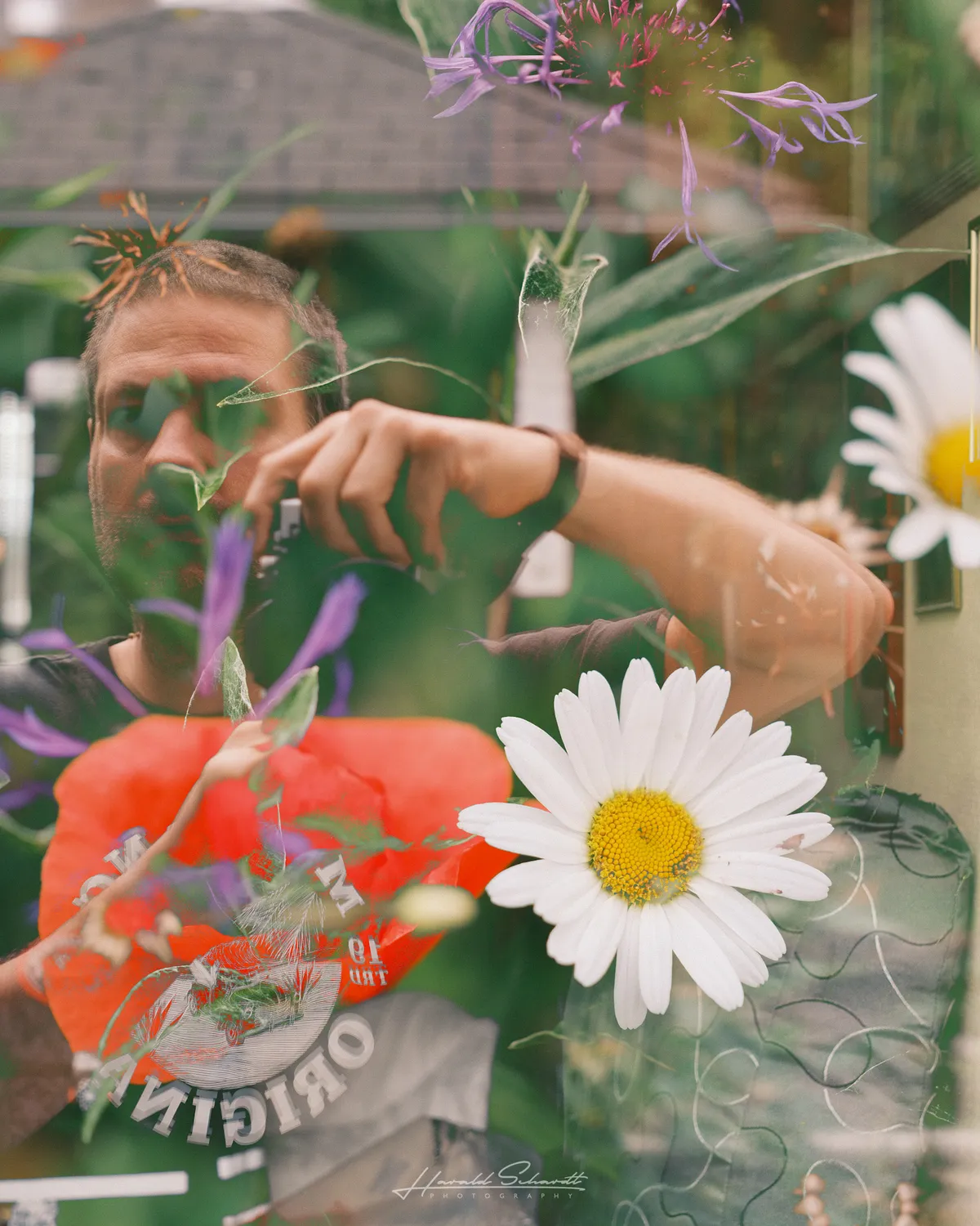 Self portrait reflected in glass, layered with colorful flowers.
