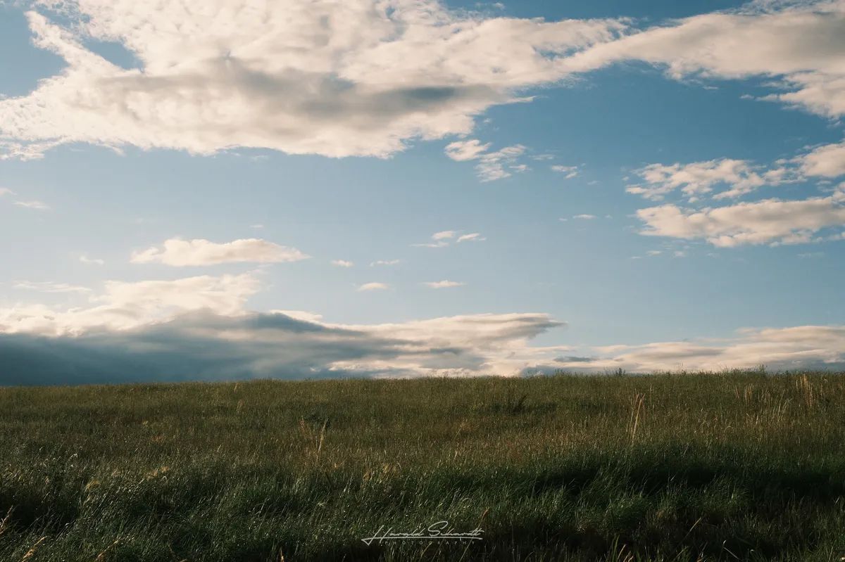 Rolling countryside under dramatic evening clouds.