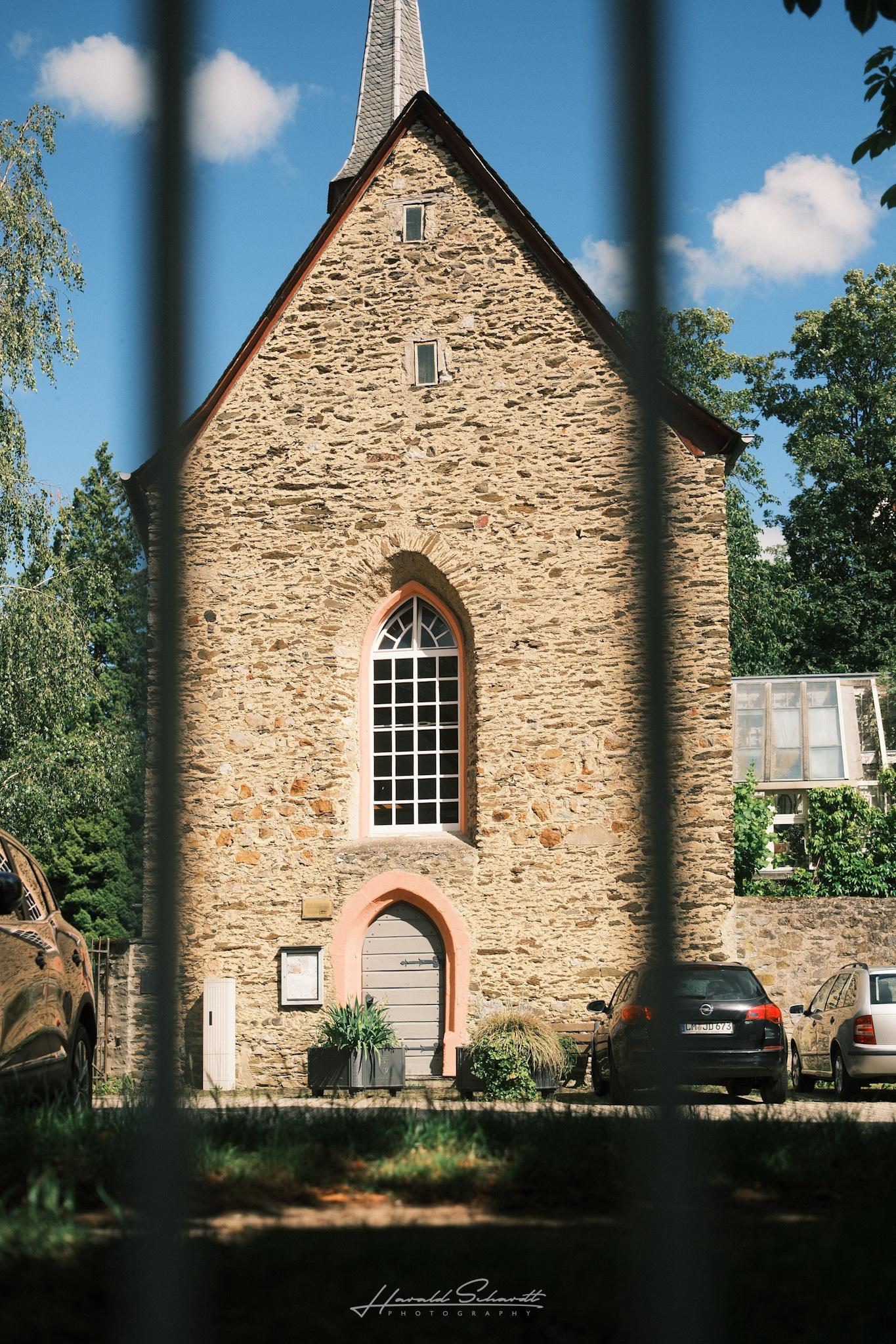 Historic stone chapel seen through a metal fence.