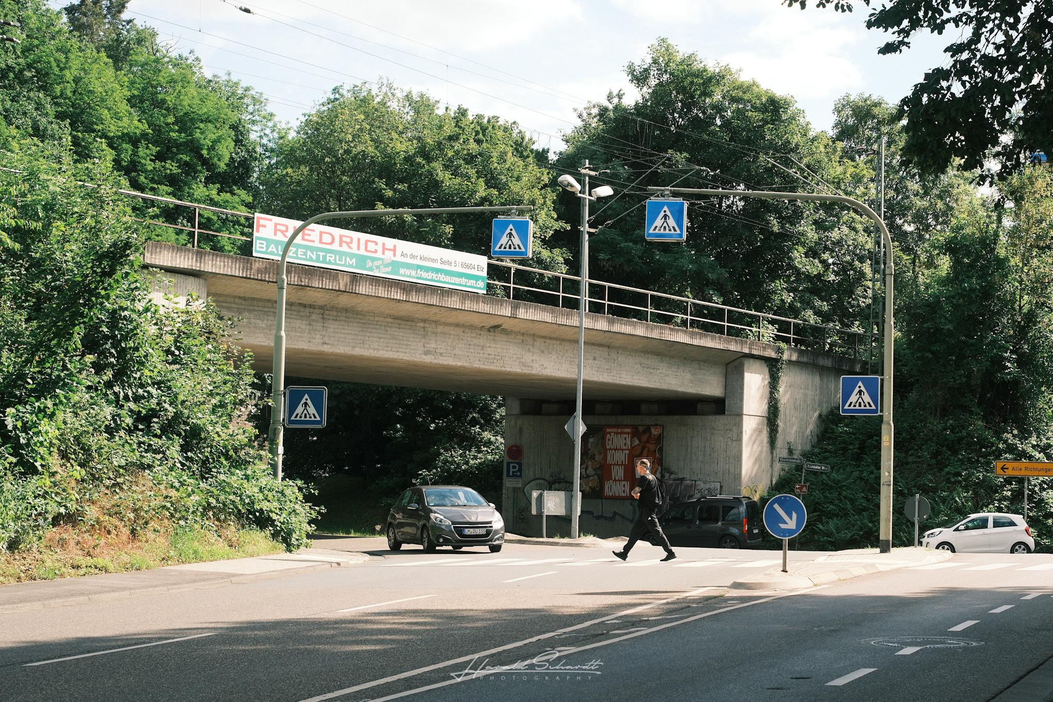 Pedestrian crossing beneath a railway bridge surrounded by trees in Limburg.