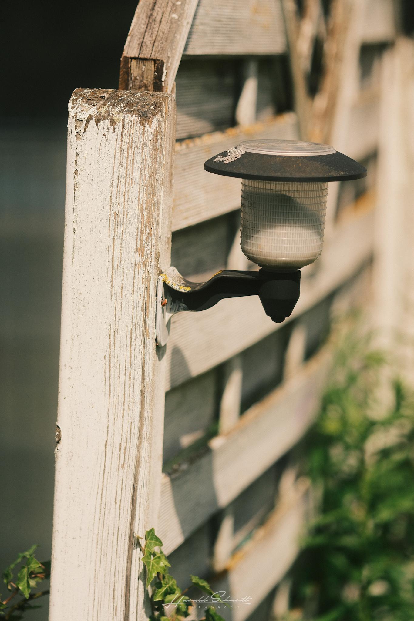 Small garden lamp attached to a wooden fence