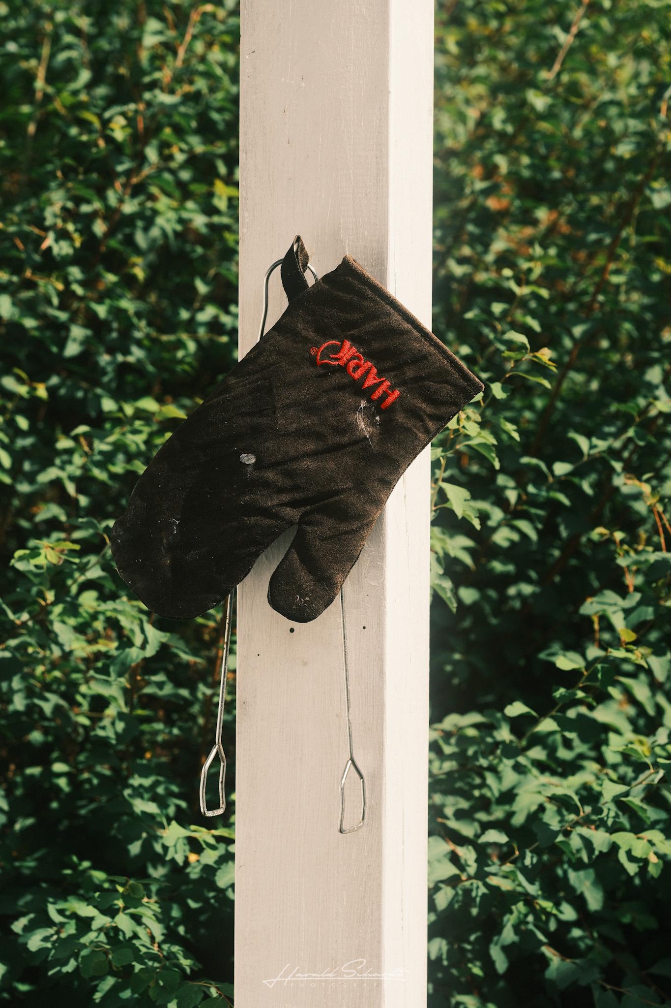 Black barbecue glove hanging on a wooden post