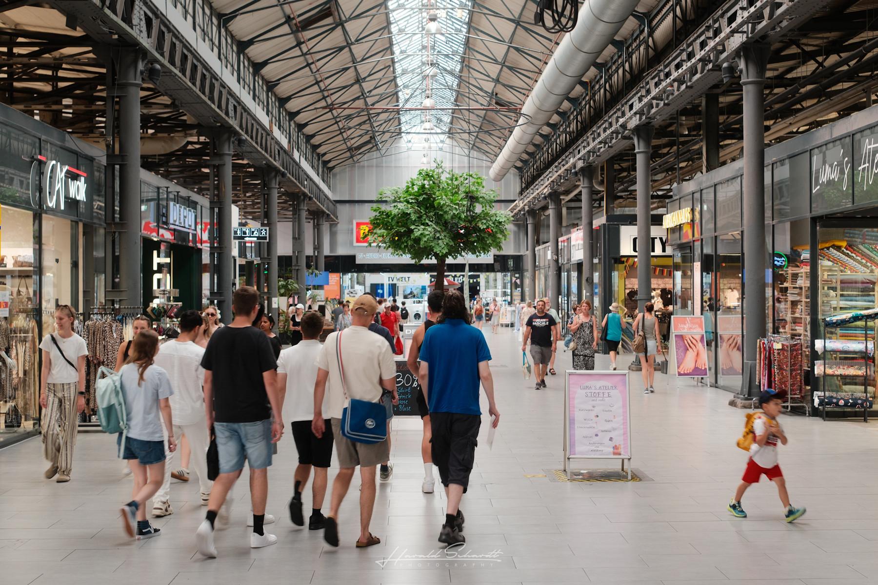 People walking through a covered shopping arcade.