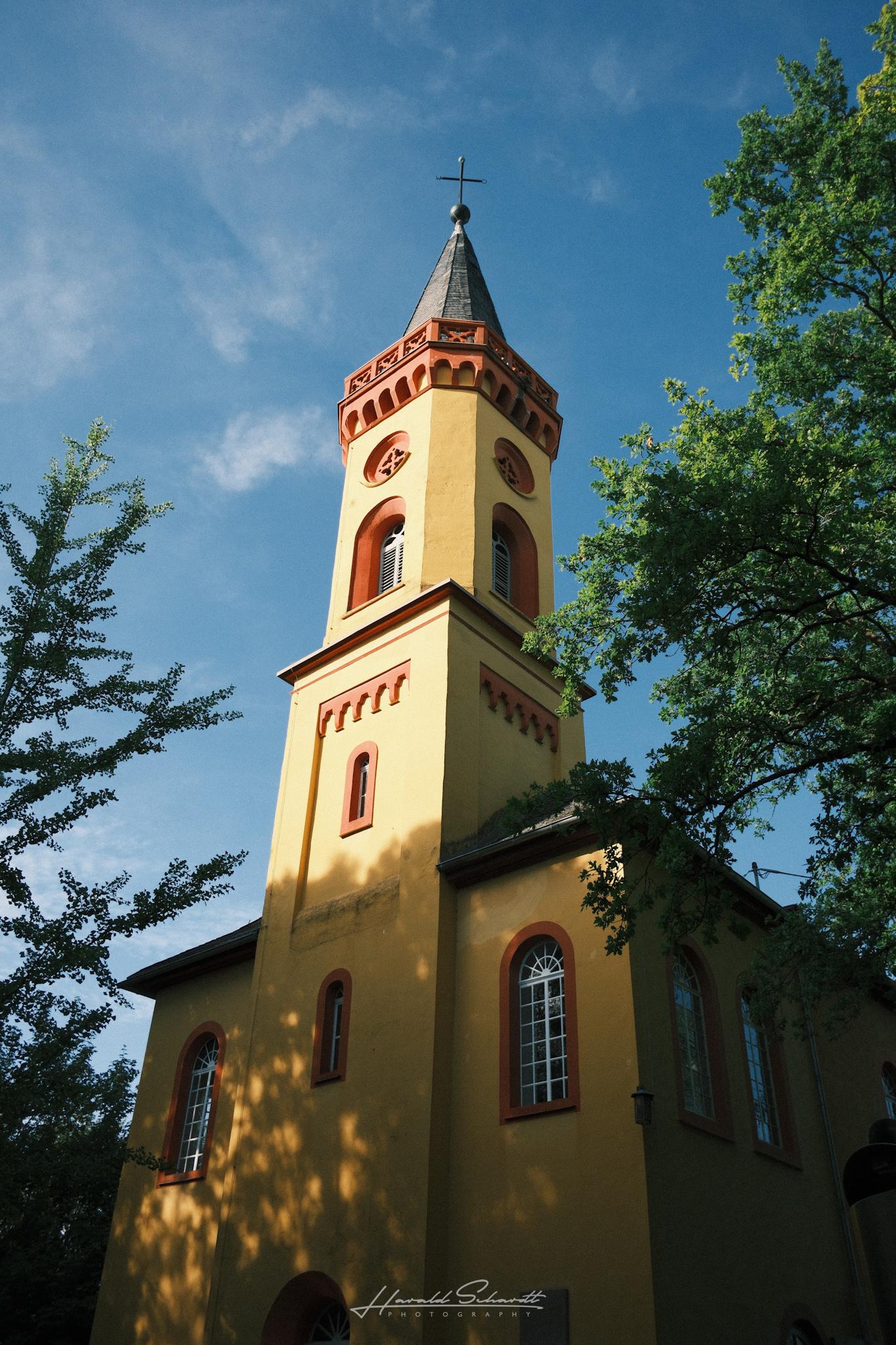 Low angle view of the same church tower, showing the full facade with arched windows and red trim.