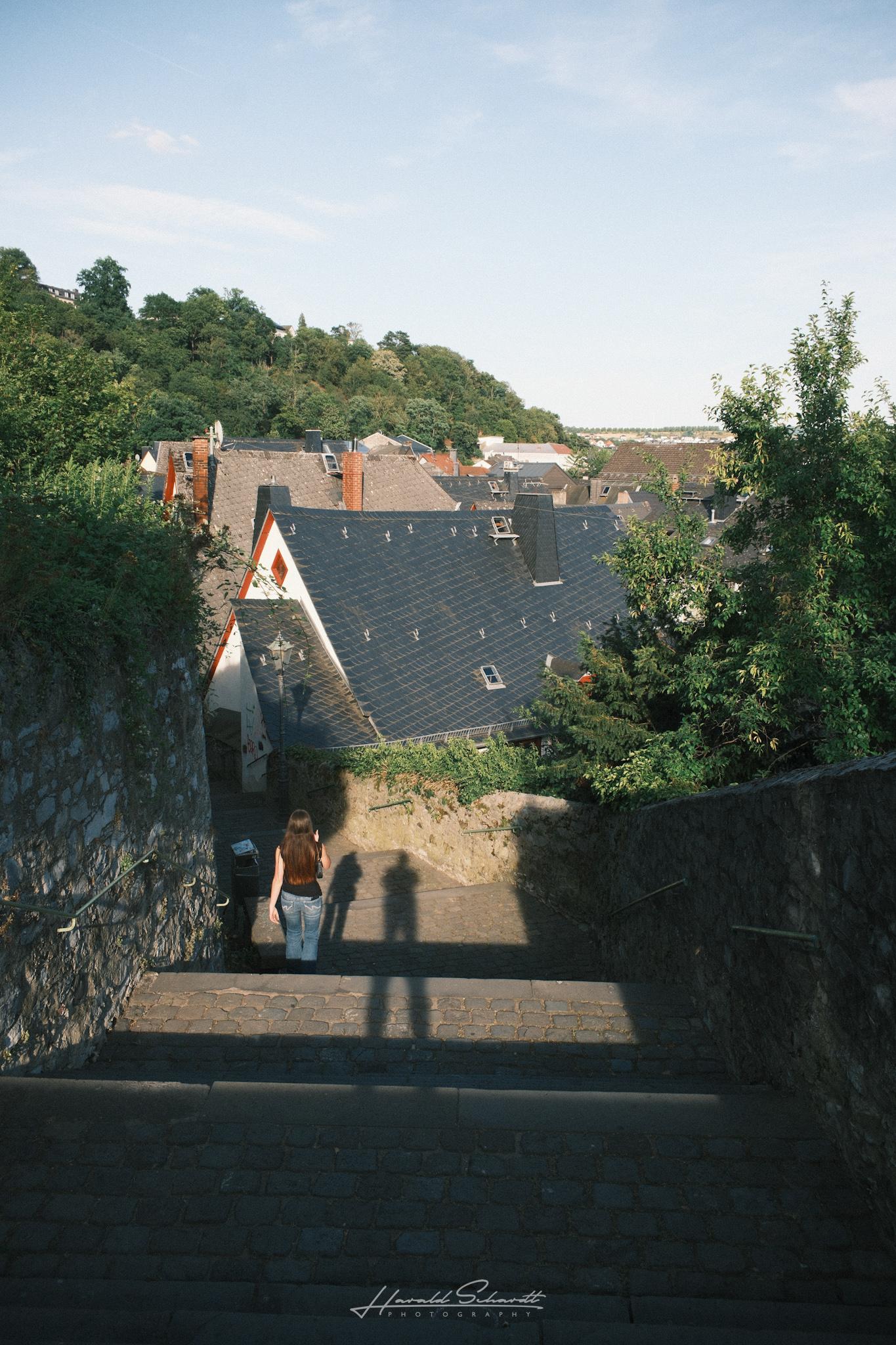 Stone steps leading down through the old town wall, a person descending, long evening shadows on the ground.