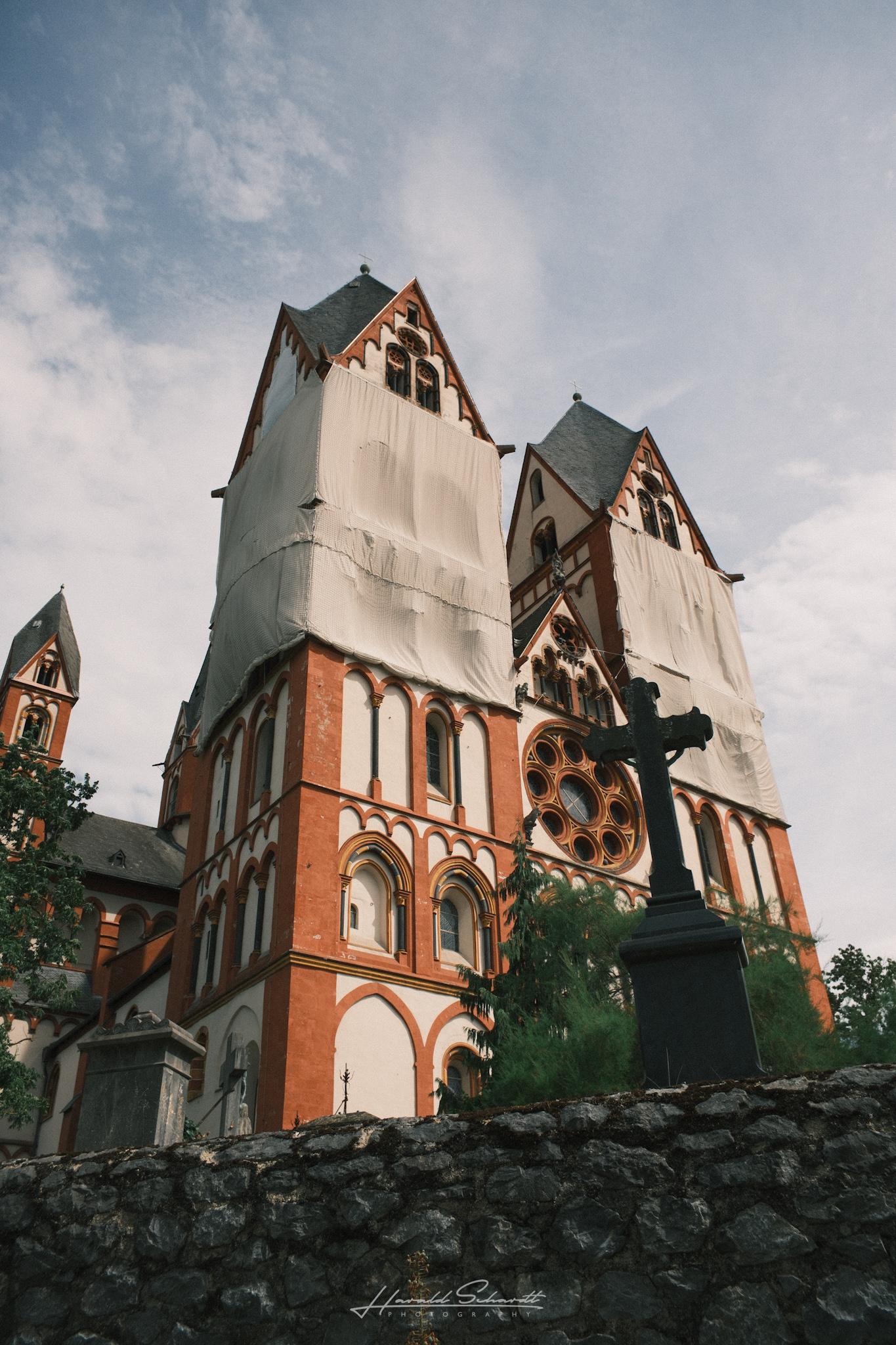 Limburg Cathedral with parts of its towers covered in protective sheeting during restoration work, viewed from below.