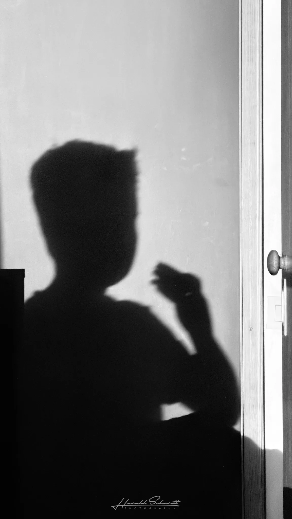 Shadow silhouette of a child eating a burrito, cast by midday sunlight onto a wall beside a door.